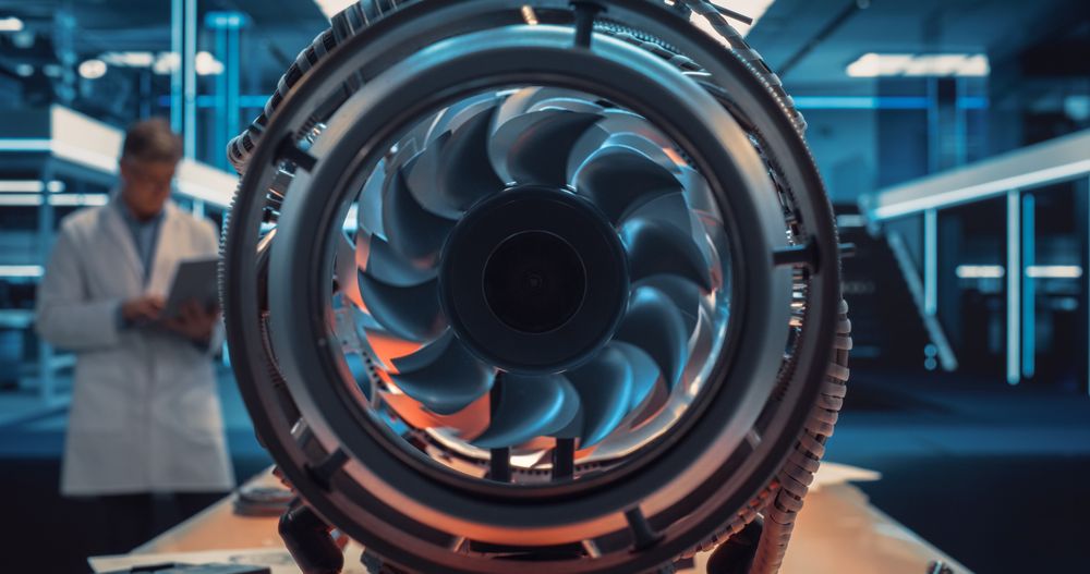 Industrial Engineer Working on a Futuristic Jet Engine, Standing with Laptop Computer in Scientific Technology Lab.