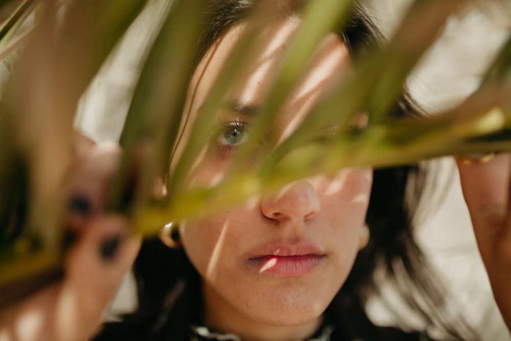 brunette woman behind palm leaf