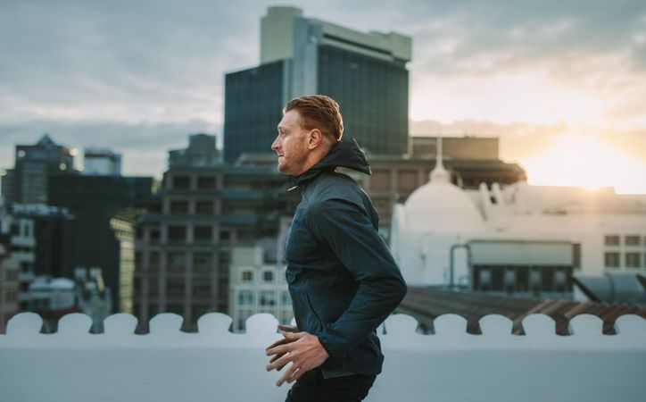 Fitness man doing exercises on the terrace of a building with sunrise in the background