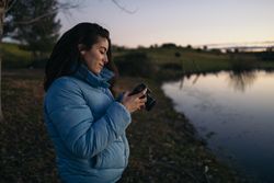 Photographer woman taking photos of a lake at sunset