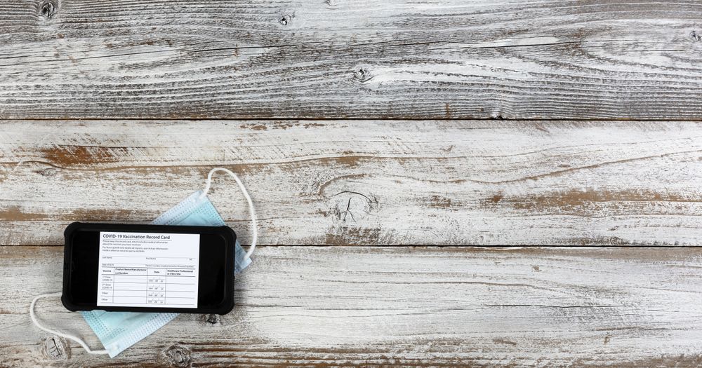 Covid 19 vaccination record card with smartphone plus facemask