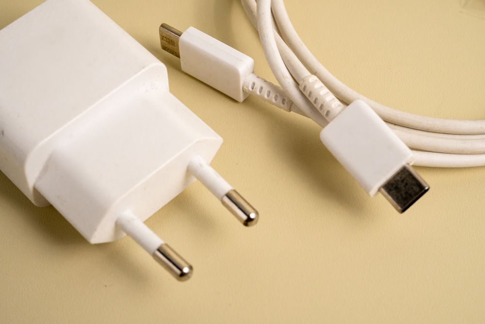 A charger and a cable are laying on a yellow surface