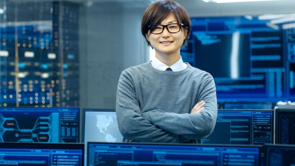 In the System Control Room IT Technician Crosses Arms and Smiles.