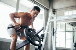 Male bodybuilding pulling up a weight in gym or fitness center