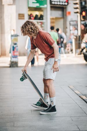 Confident man riding longboard across city street