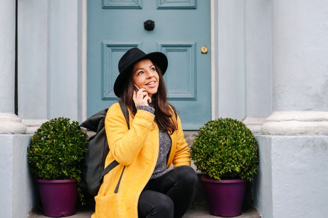 Happy female talking on smartphone on doorstep