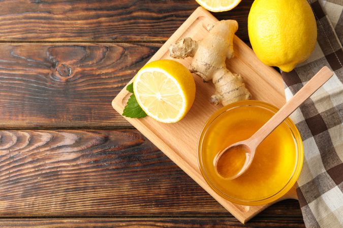 Honey, ginger, lemons and towel on wooden background, top view