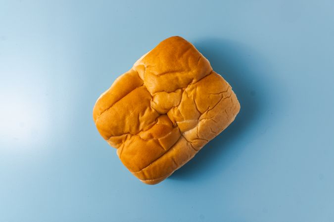 A single loaf of bread placed on a solid blue surface