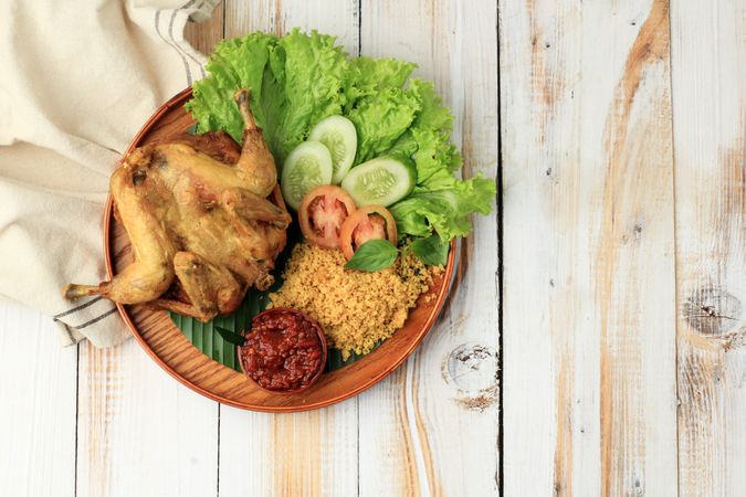 Top view of Indonesian chicken dish served with salad and spicy sauce