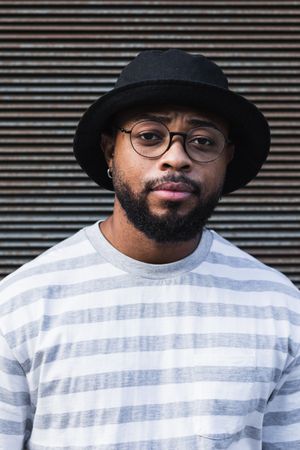 Black hipster man in hat looking at camera