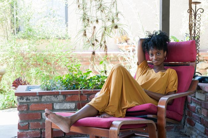 Woman in yellow dress lounging on chair near garden