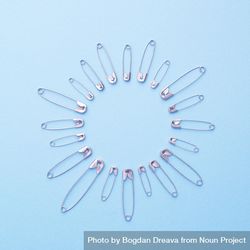 Safety pins in a circle shape over blue background 4mDpW5