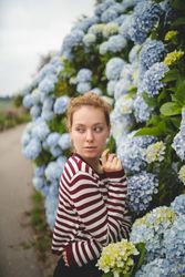 Peaceful woman near blue hydrangeas