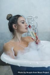 Dreamy woman in bathtub enjoying a glass champagne 0VyGGb