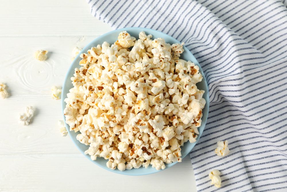 Flat lay composition. Towel and plate with popcorn on wood background