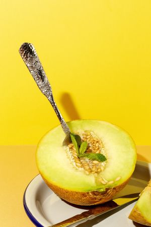 Sliced small melon on plate with spoon and fork