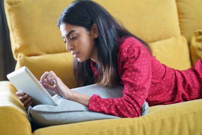Female relaxing at home while reading on a tablet