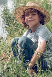 Smiling boy sitting on river shore on grass