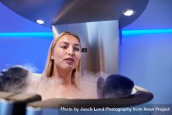Blonde woman in cryotherapy chamber looking out over the top 0V6g9v