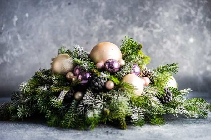 Side view of purple and gold Christmas baubles in pine centerpiece
