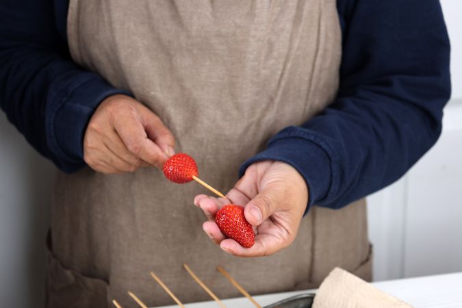 Female Hand Making Fruit Skewers with Fresh Strawberry