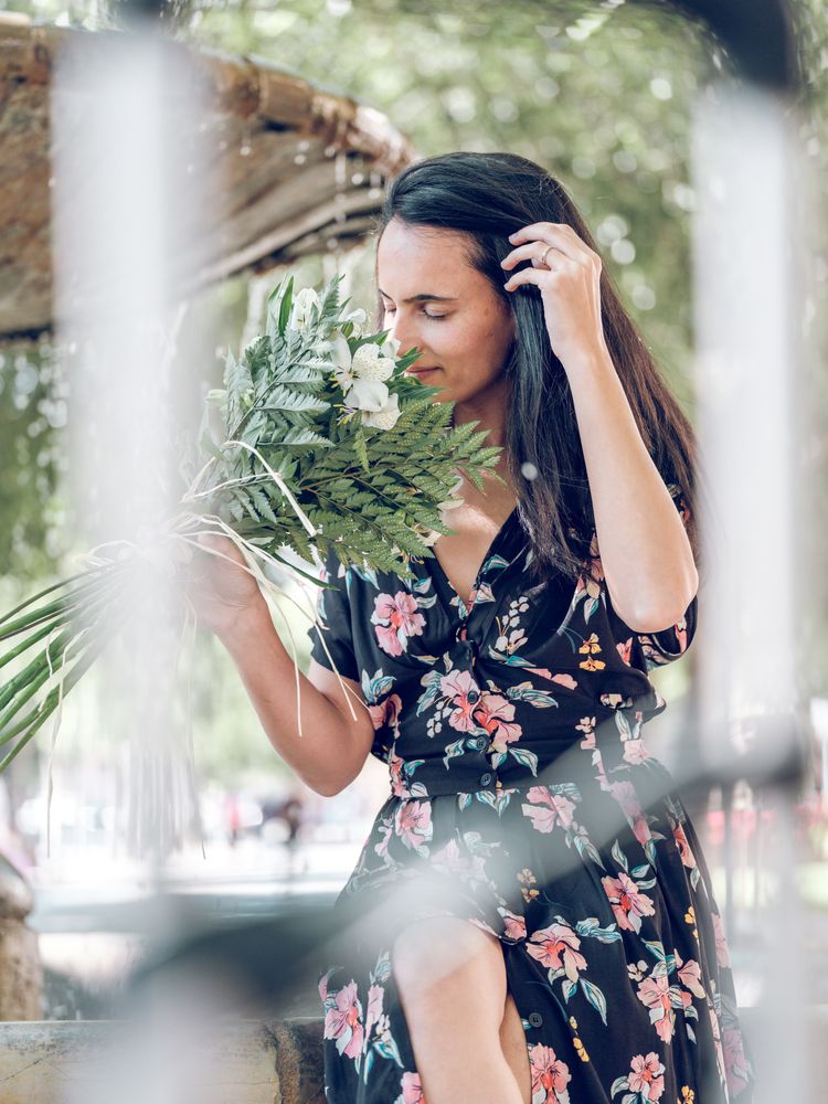 Young female smelling bouquet of flowers resting in park