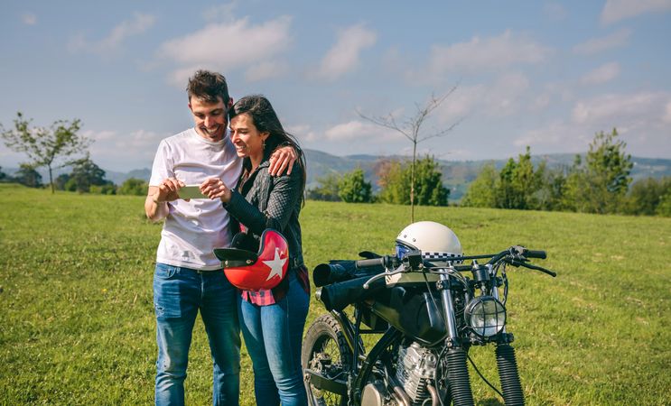Couple looking mobile with a motorcycle
