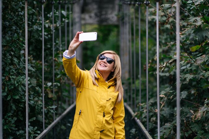 Happy female traveler taking selfie on suspension bridge in summer