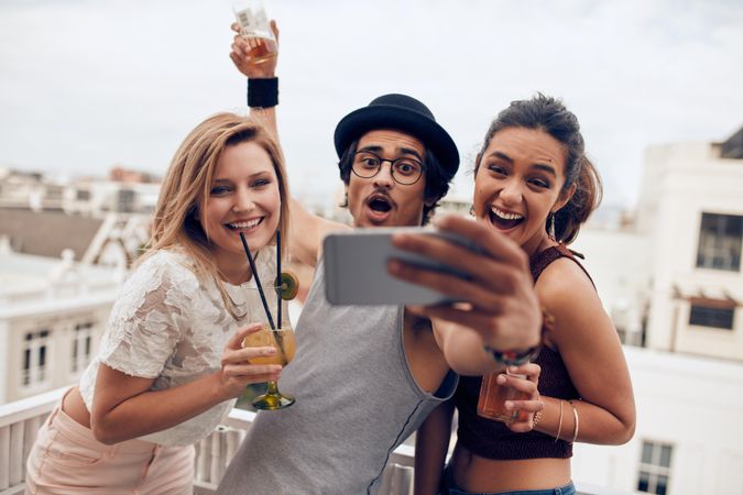 Excited young people taking self portrait with mobile phone during a party