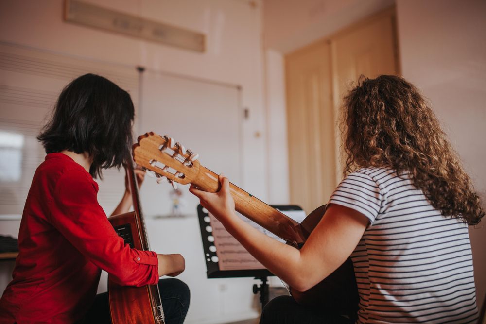 Two students concentrating on learning new music for guitars
