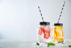 Melted crashed ice and mint leaves around, striped drinking straw inside rustic jars