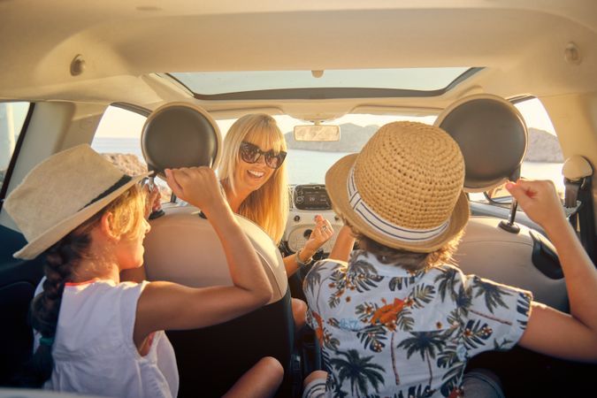 Mother turning in the seat of a car and looking at her children