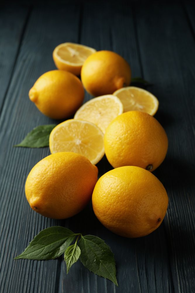 Fresh lemons and leaves on wooden background. Ripe fruit
