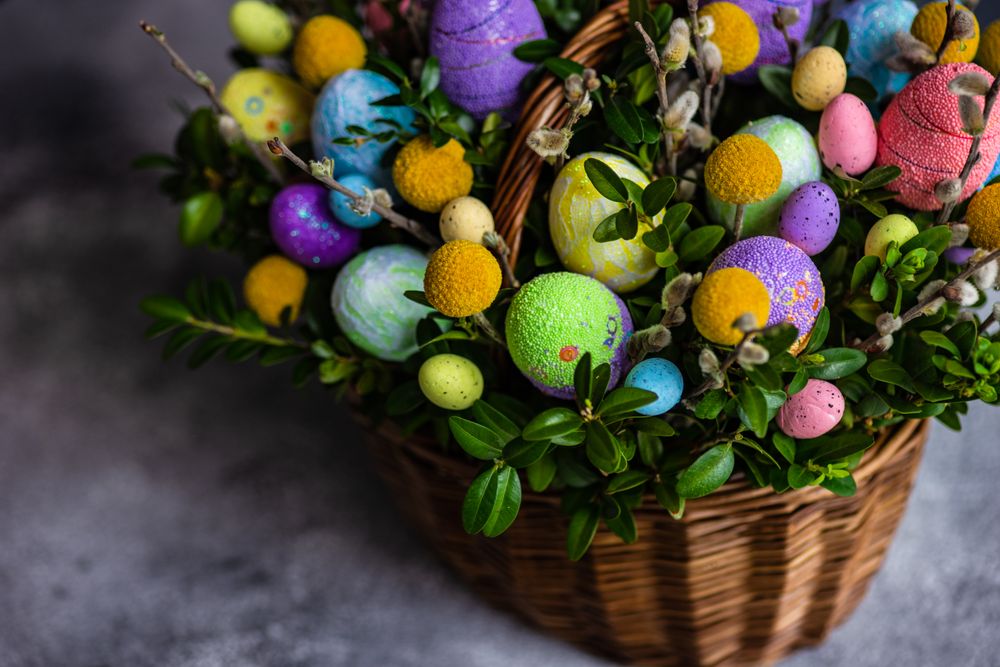 Colorful Easter eggs & leaves in decorative basket