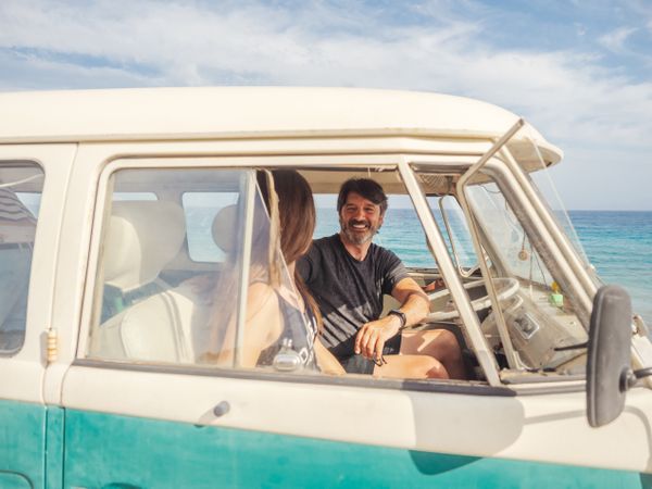 Man and woman watching and discussing blue thing in car