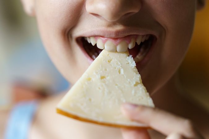 Teenager smiling while biting into cheese