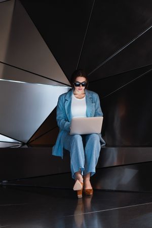 Woman in sunglasses browsing laptop in studio