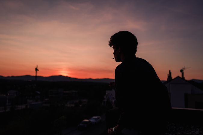 Young man smoking cigarette during sunset