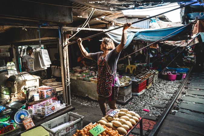 Woman wearing an apron standing beside a stand at the street market