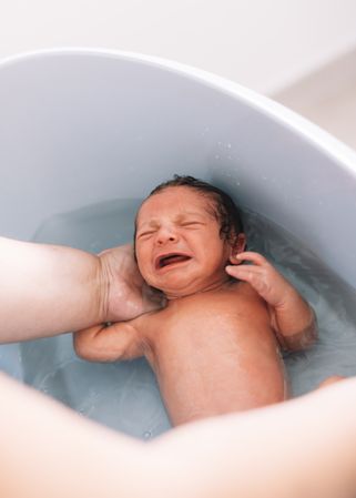 Anonymous parent washing infant in basin