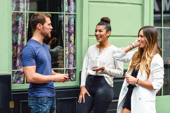 Multiracial group of friends talking next to green wall outside