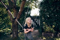 Blonde girl smiling with braided hair sitting on outdoor swing