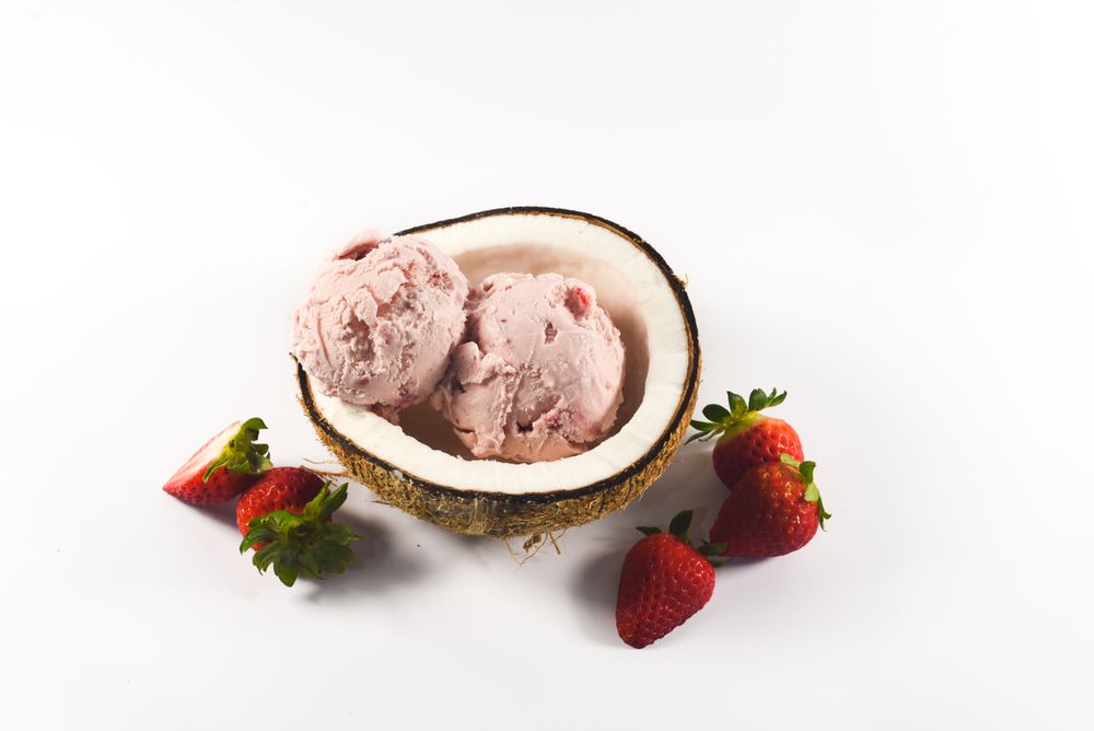 Top view of coconut shell with strawberry ice cream and fruit halves