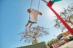 Man swinging on playground in sunlight