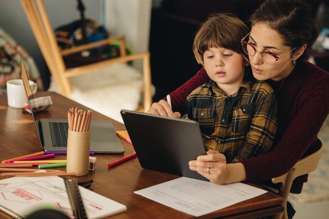 Mother teaching son how to draw on digital tablet