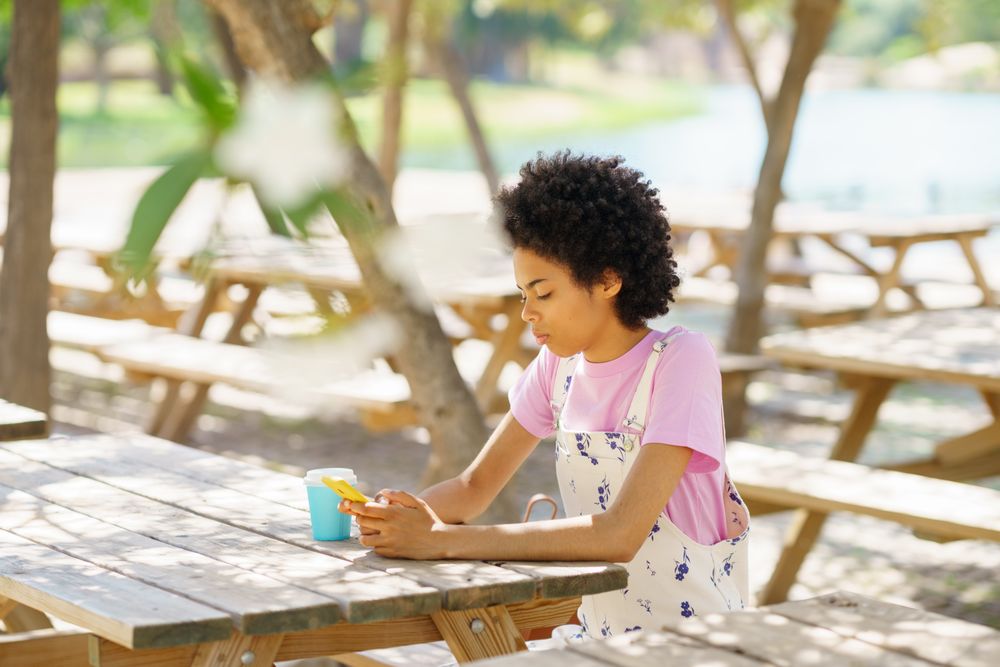 Woman sitting on park table texting
