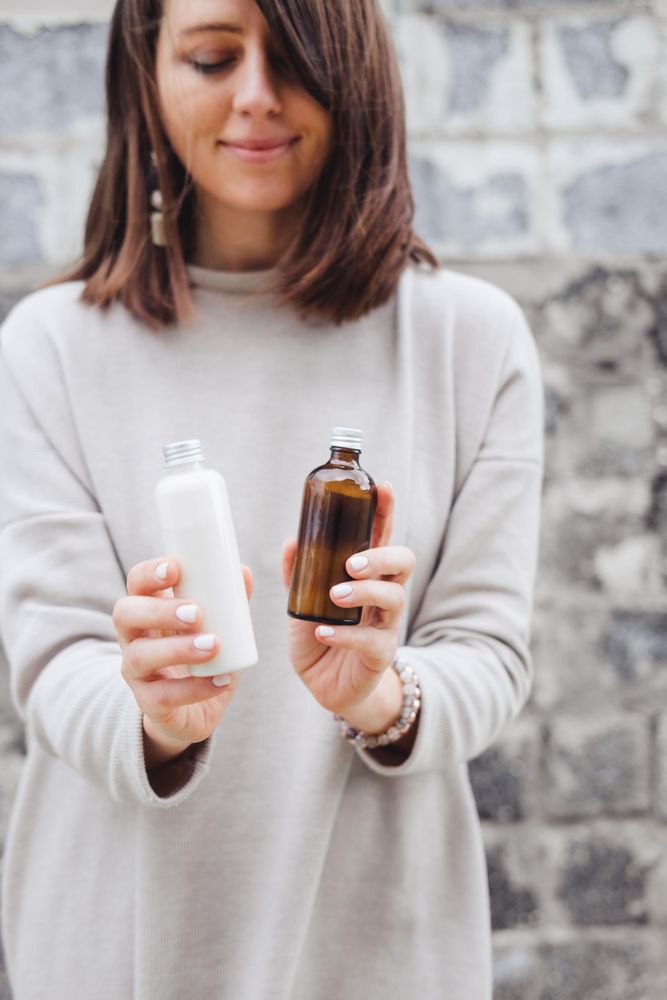 Portrait of Woman shirt holding two glass bottles