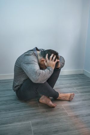 Unrecognizable man with problems sitting on the floor