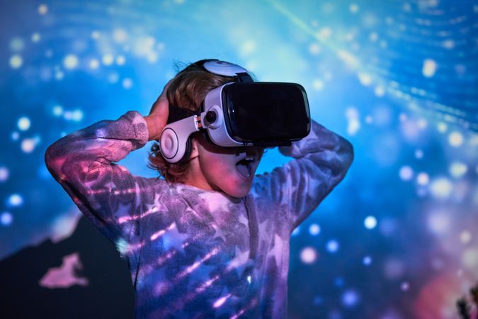 Excited kid in virtual reality glasses looking away with opened