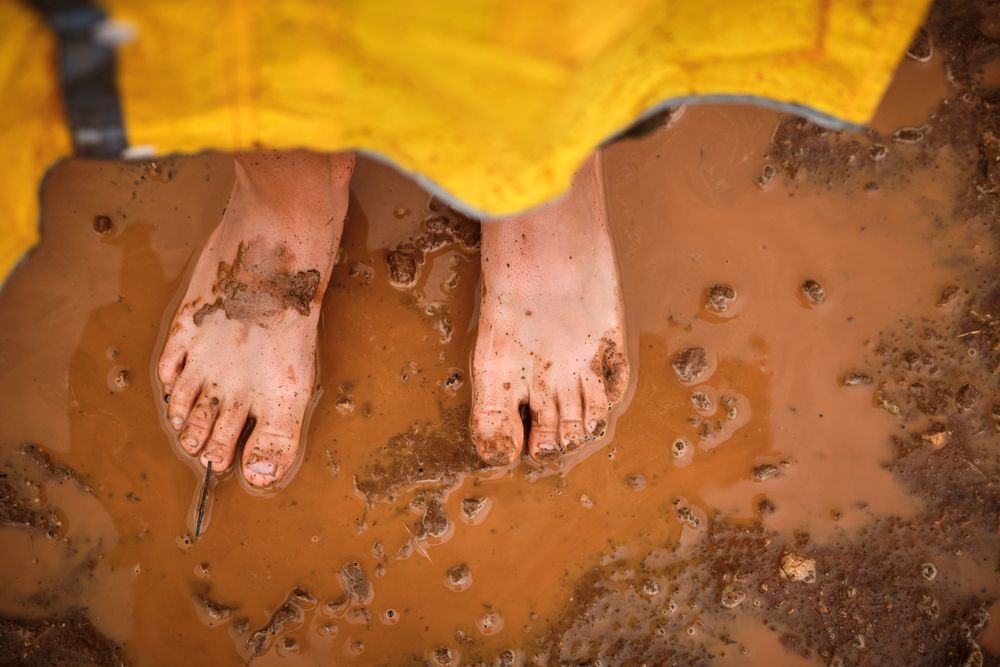 Dirty feet of crop person in puddle